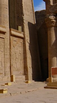 Grand courtyard of the Temple of Edfu with massive columns and monumental facade, showcasing the preserved grandeur of Ancient Egyptian architecture under clear blue sky