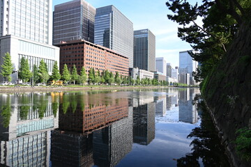 皇居外苑の水辺に映る高層ビル群と並木が描く都会の風景   Urban skyline reflected on the waters of Kōkyo Gaien with tree-lined paths  © 拓也 山並