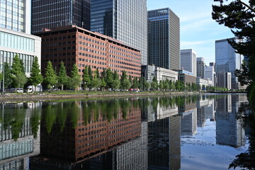 皇居外苑の水辺に映る高層ビル群と並木が描く都会の風景   Urban skyline reflected on the waters of Kōkyo Gaien with tree-lined paths  © 拓也 山並