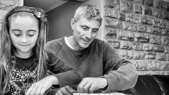 Happy father playing table game with his young daughter