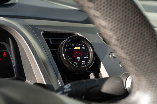 Black Honda Civic Si interior with AEM oil pressure gauge in air vent, Sport compact sedan modified dashboard view