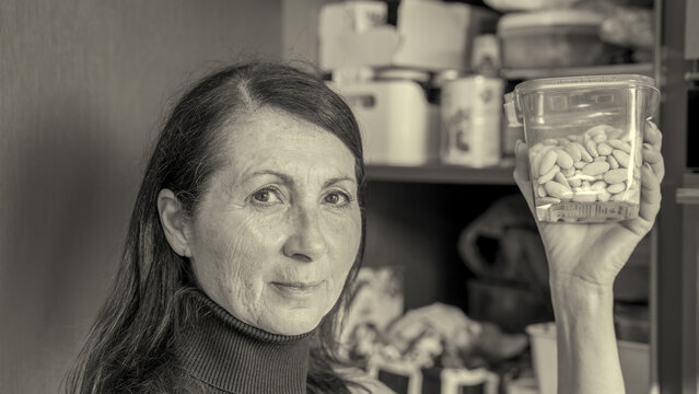 Woman in kitchen holding container of almonds for healthy food preparation