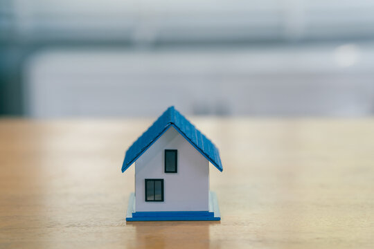 Small house model with blue roof placed on wooden table