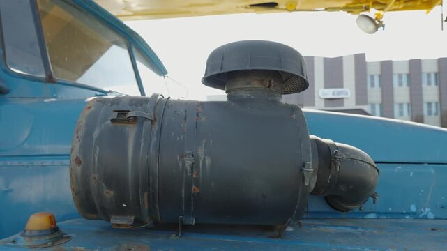 A large black air filter housing mounted on blue truck.