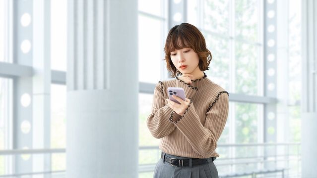 スマートフォンを使って考える女性・ビジネスウーマン, Businesswoman Thinking While Using a Smartphone