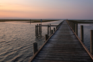 Fototapeta premium Sunset view from a wooden boardwalk across the Grado Lagoon, Italy