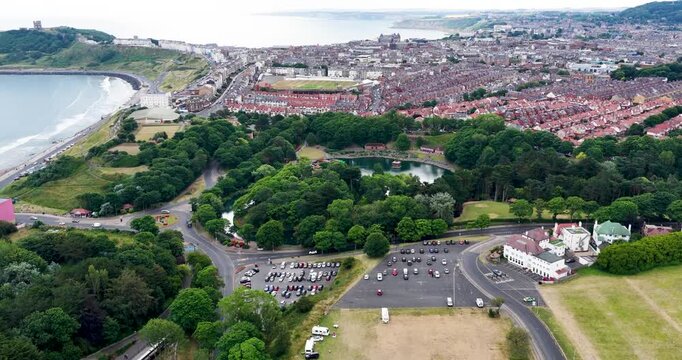 Aerial footage of Peasholm Park and Scarborough overlooking the North Sea with the boating lake Scarborough Castle and Scarborough Cricket Club surrounded by the historic seaside town in Yorkshire UK