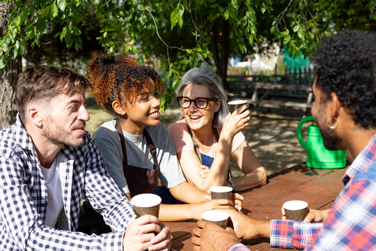 Diverse group of gardeners enjoying coffee break in community garden