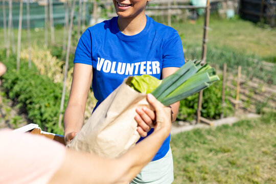 Volunteer giving fresh produce in community garden