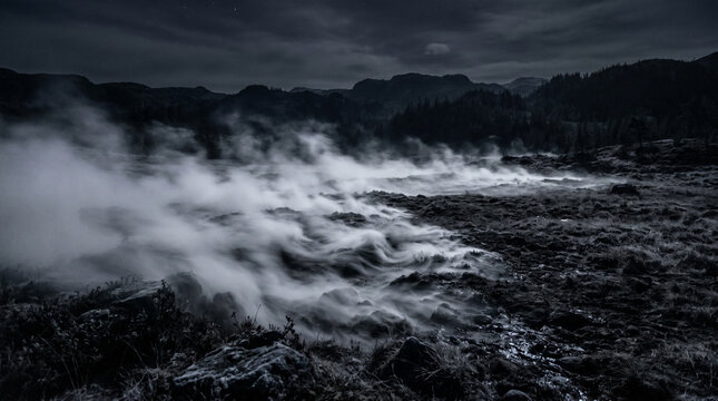 Moody monochrome mountain range under heavy mist and clouds.