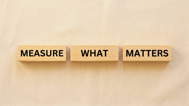 Wooden blocks spelling Measure What Matters with ruler prop overhead square, performance measurement concept