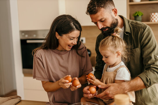 Family cooking breakfast together in kitchen with eggs