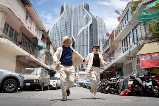 Active Senior Men Running Joyfully in the City Alley, Modern Skyscraper Background