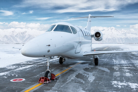 White bizjet at winter airport on the background of high scenic snow capped mountains