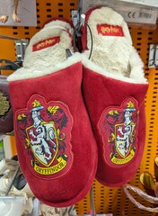 Fototapeta premium Par de pantuflas de color rojo con el logo de Harry Potter y el escudo de la Casa de Gryffindor del Colegio Hogwarts de Magia y Hechiceria, tienda Toy Planet de Madrid, España, 15 de mayo de 2026
