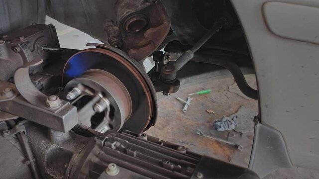 Car brake disc rotor being resurfaced by an on-car brake lathe machine in a mechanic garage