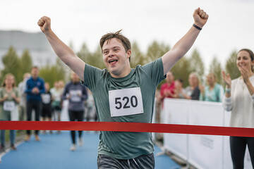 A young man with number 520 cheering with arms raised during an outdoor race or event.