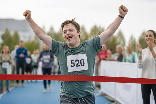 A young man with number 520 cheering with arms raised during an outdoor race or event.