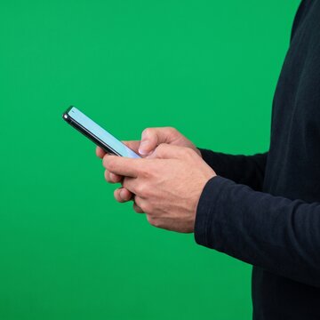 Person holding a smartphone on green background