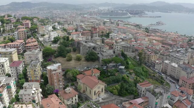La Spezia, Italy. Castle of San Giorgio, medieval stone fortress with crenellated walls and pentagonal towers, Drone footage over terracotta rooftops and the Ligurian Gulf. Drone footage, Point of in