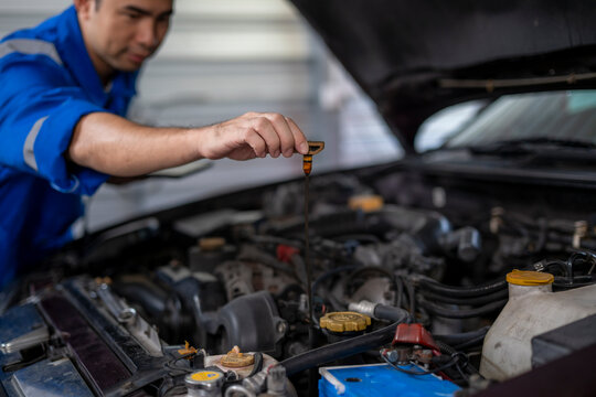 Car mechanic checking engine oil level using dipstick
