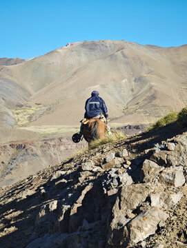 Traditional horseman traveling through the rugged Andes mountain range in Patagonia