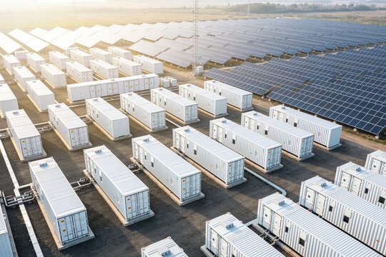 Large solar farm with rows of battery storage containers and solar panels