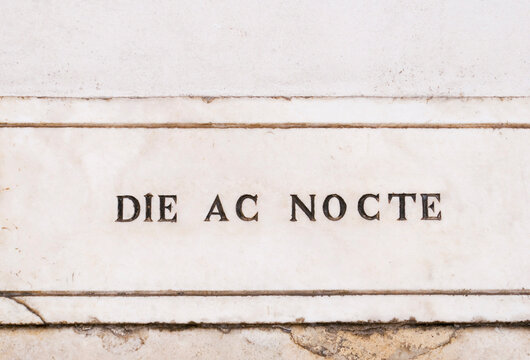 Latin sentence meaning  "day and night"carved on marble plaque on the wall of a church