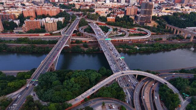 Highbridge highway interchange beside the Harlem River. Aerial view shows bridges, looping ramps, traffic, rail lines and Bronx apartment blocks.