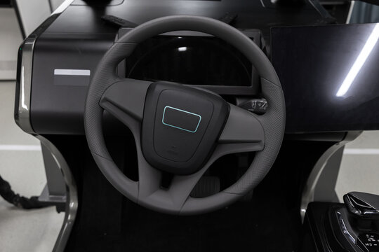 Steering wheel of a modern car simulator system featuring digital dashboard and touchscreen displays with a joystick control, conveying advanced automotive and education technology
