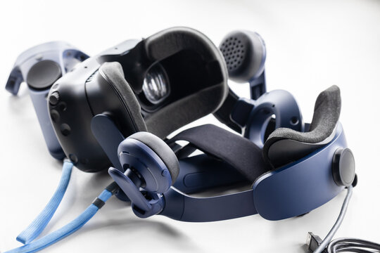Blue virtual reality headset paired with controllers and integrated over-ear headphones, ideal for immersive gaming, simulation, and tech demos. Close-up photo on white background with selective focus