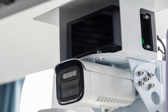 Close-up of a white security camera mounted indoors, highlighting CCTV surveillance technology and monitoring equipment used for building security, safety, remote observation and video inspection