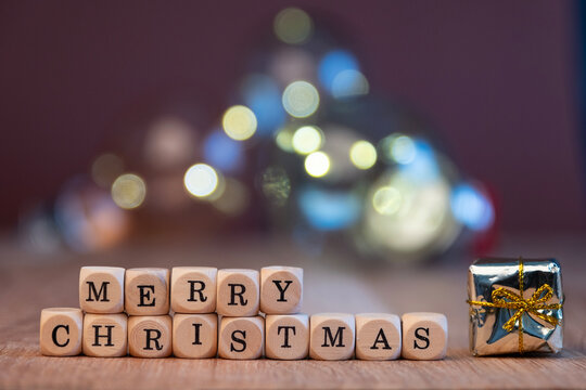 Small wooden blocks with the inscription Merry Christmas. Blurred Christmas lights in background
