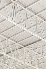 Fototapeta premium White Metal Roof Structure and Steel Truss Framework,Close-up view of a modern white metal roof structure featuring geometric steel truss patterns, architectural support beams, and industrial ceiling 
