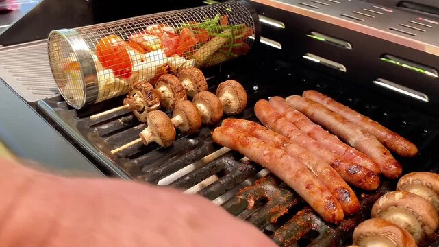  Close Up of Man Hand Flipping Mushroom Skewers on Gas Grill with Sausages