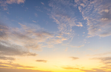Obraz premium Dramatic golden hour sky with soft clouds at sunset,A beautiful and serene view of a golden hour sky, featuring soft, wispy clouds illuminated by the warm, gentle light of the setting sun, creating.