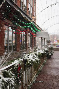 Snow-covered holiday greenery and colorful lights along a street in downtown Naperville, Illinois