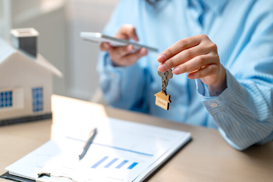 Close up hand of woman with blue shirt hold the key with the other hand work with mobile phone.