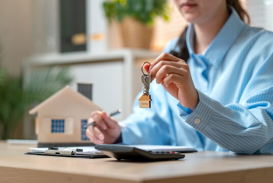 Woman with blue shirt hold the key with the other hand hold pen and touch on table.