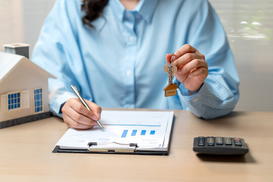 Front view of woman with blue shirt hold the key with the other hand write the data on graph paper on table.