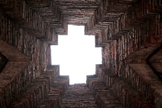 Abstract Brickwork Sky View: An abstract perspective looking directly up into a geometric ceiling made of brick, with a bright square of sky visible through the opening.