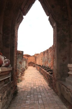 Ancient Temple Pathway: A weathered brick pathway leads through the ruins of an ancient temple, its arched entrance framing a bright sky.