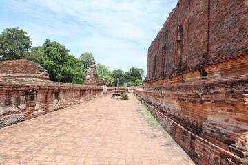 Fototapeta premium Ancient Temple Ruins in Asia: An atmospheric perspective of weathered brick walls and ancient stupas, with lush greenery in the background.