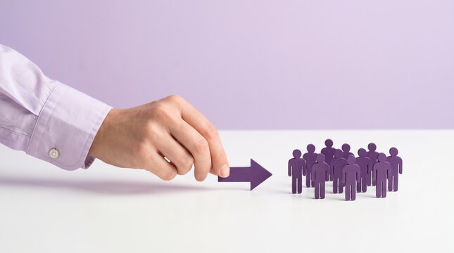 Business leadership concept with hand pointing arrow at group of people, corporate team management and human resources strategy, purple figures on white desk