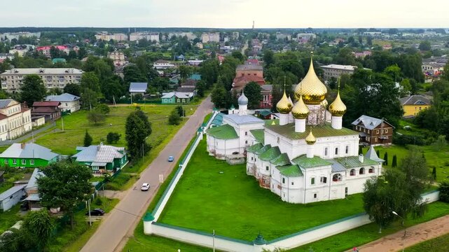 Uglich, Russia. Resurrection Monastery, golden onion domes and white stone ensemble, Drone footage over the Volga River with the Uglich Hydroelectric Station dam in the background. Drone footage, Dep