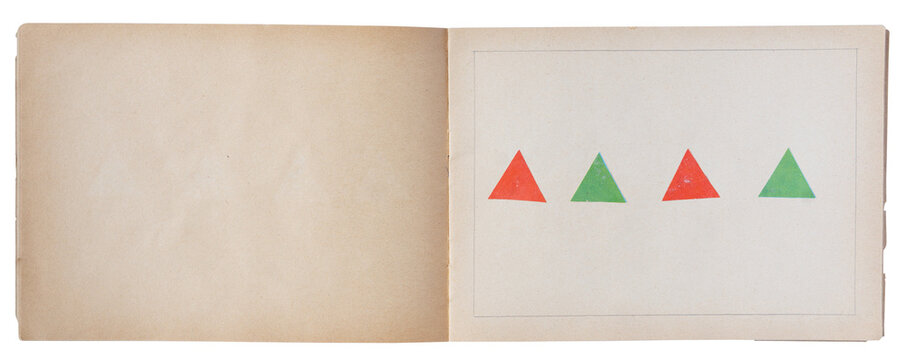 Open vintage book with red and green triangle illustrations on blank page, top view
