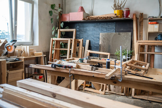 Professional restoration workshop interior with tables, wooden materials, tools and instruments, creative workspace for repair and carpentry production, handmade woodworking job, wood craft room.