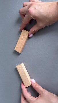 Hands moving wooden blocks toward each other against gray background. The video represents concepts of opposition, confrontation, negotiation and conflicting viewpoints.