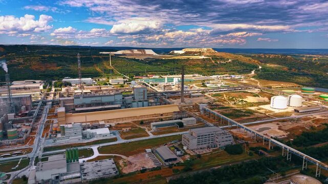 Footage over the huge industrial plant at daytime. Beautiful nature landscapes in the backdrop.