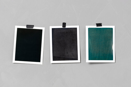 three blank photo print taped to a textured grey wall with black adhesive tape